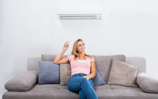Woman on couch next to a ductless air conditioning system | Keith Air Conditioning