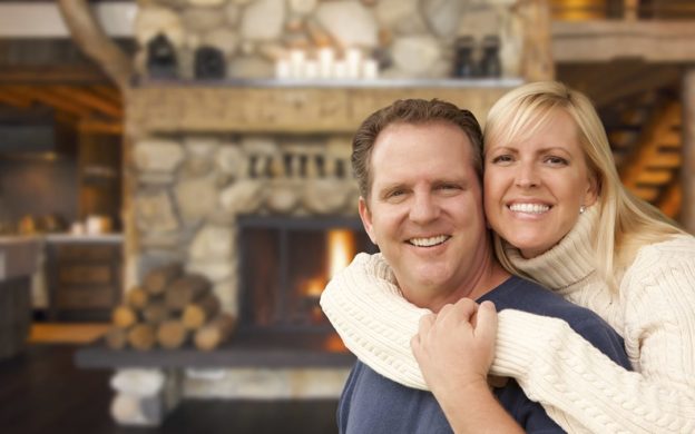 Man and woman hug in front of fireplace | Don’t Wait to Book HVAC Repairs and Maintenance | Keith Air Conditioning