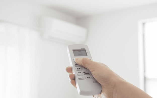 Ductless Air Conditioner and Hand with Remote | Ductless Air Conditioners Hidden Benefits | Keith Air Conditioning